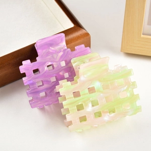 Detail view of hollow square hair claws with marble texture in purple and pink tones