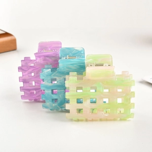 Detailed view of hollow square hair claws in purple, blue and green marble acetate