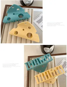 Close-up of yellow and blue cheese shaped claw clips with hollow cutouts on jewelry tray