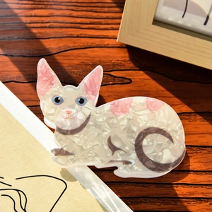 Detail of cute cat-shaped acetate hair claw clip showing pearly white texture and pink accents