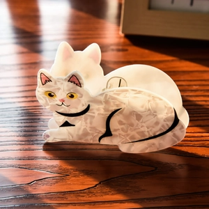 Detailed close-up of a white marble texture cat-shaped hair claw on a wooden surface