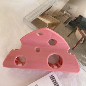 Close-up of pink cheese-shaped hair claw clip with hollow triangular Swiss cheese texture