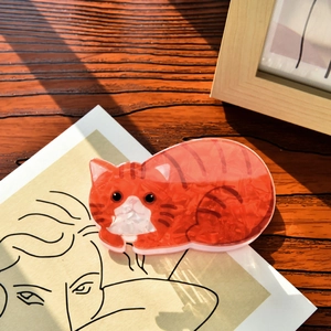 Detailed macro view of orange marble acetate cat hair claw clip on wooden desk