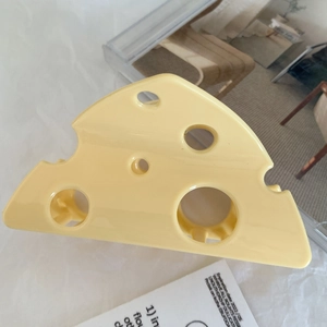 Detail view of a yellow cheese-shaped hair claw clip with hollow triangular design