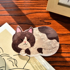 Detailed close-up of a cute cat-shaped hair claw clip with a marbled acetate texture