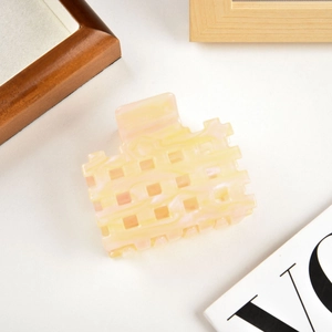 Close-up of marble-patterned yellow acetate hair claw clip with hollow square design
