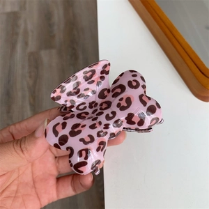Gros plan d'une pince à cheveux papillon rose brillant avec un motif léopard marron