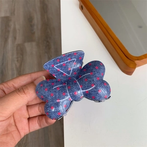 Détail d'une pince à cheveux en jean bleu à pois roses montrant texture et fixation