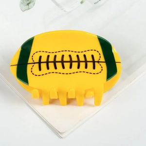 Dettaglio della pinza per capelli a forma di rugby in acrilico giallo con strisce verdi