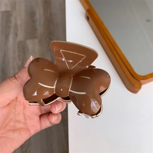 Détail de la grande pince à cheveux marron en forme de nœud avec finition brillante
