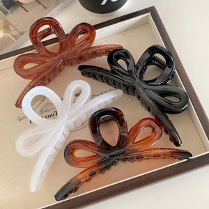 Set of four large bow hair claw clips in amber, black, and cream colors for women
