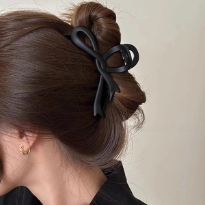Matte black oversized bow hair claw clip for women shown on a model's elegant hairstyle