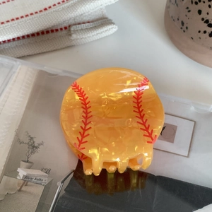 Detailed view of yellow baseball hair claw clip with realistic red stitching patterns