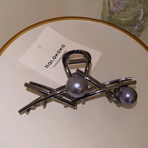 Detailed close-up of gunmetal hair claw with purple pearls on a display card