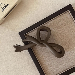 Detailed macro view of a large matte brown bow-shaped claw clip on a wooden tray