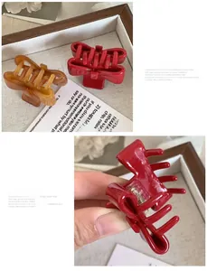 Detail view of small bow hair claws in red and amber resin with strong gold metal springs