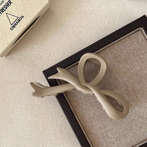 Detailed view of matte khaki hair claw clip with elegant ribbon bow design and metal spring