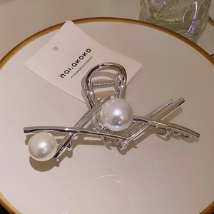 Detailed view of silver metal hair claw clip with large pearls on ceramic plate