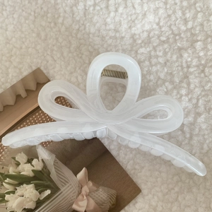 Detail of a large cream bow-shaped hair claw clip made of smooth acrylic material