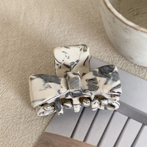 Detail of a small acetate bow hair claw clip with black and white marble pattern texture