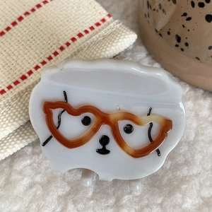 Detalle de una pinza para el pelo de perro blanco con gafas marrones en forma de corazón