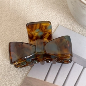 Detail view of small amber tortoiseshell bow hair claw clip made of acetate resin material