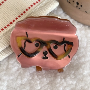 Vista detallada de la pinza para el pelo de cachorro rosa con gafas de corazón en felpa