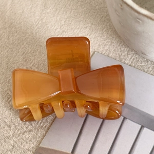 Detailed close-up of amber acetate bow hair claw with semi-transparent creamy texture
