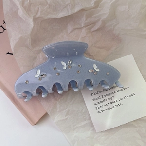 Close-up of acetic acid hair claw clip with rhinestones and white butterfly ornaments