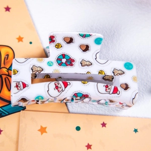 Gros plan sur une pince à cheveux carrée avec motifs de Noël et Père Noël