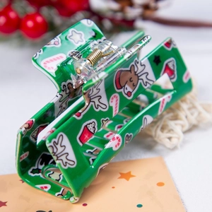 Détail d'une pince à cheveux de Noël verte avec motifs de rennes et de cannes de sucre