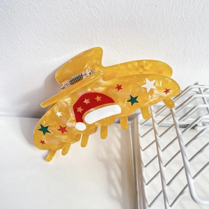 Détail d'une pince à cheveux de Noël jaune translucide avec des motifs d'étoiles
