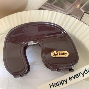 Detail of dark brown acetate hair claw clip featuring a golden teddy bear metal plate decoration