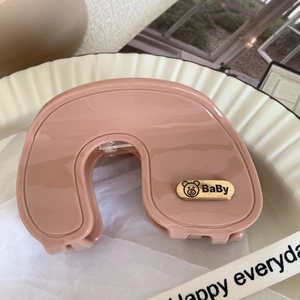 Detailed shot of pink hair claw clip with golden baby bear logo on a white tray