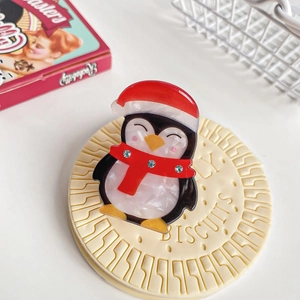 Detailopname van pinguïn haarklem met kerstmuts en strass sjaal op koekjesstandaard