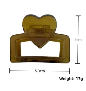 Dettaglio macro della molletta in acetato ambra con cuore, misura 5,3 cm di lunghezza e 4 cm