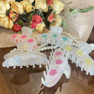 Set of 5 iridescent resin hair claw clips with rhinestone flower accents on wooden surface