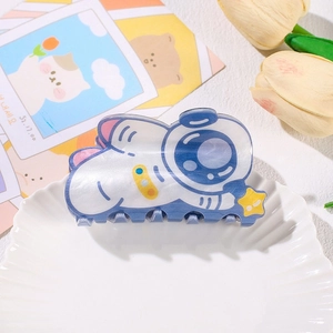 Macro view of blue pearlescent astronaut cat hair claw clip on white ceramic plate