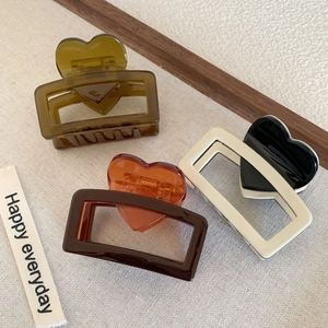 Tre eleganti pinze per capelli a cuore in acetato nei colori ambra, caffè e crema