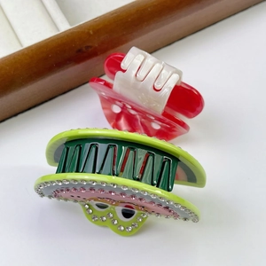 Dettaglio di fermagli per capelli in acetato con motivi di melone verde e fungo rosso