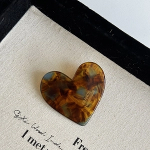 Close-up of heart-shaped hair clip with leopard tortoiseshell texture and gold lettering