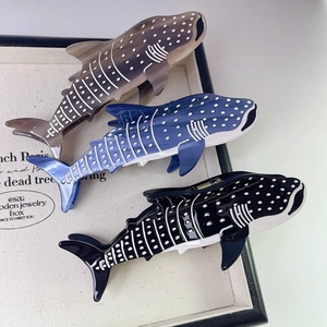 Détail de trois pinces à cheveux en acétate motif requin-baleine en bleu, noir et gris