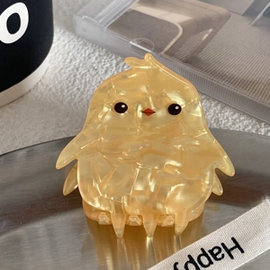 Gros plan d'une jolie pince à cheveux poussin jaune en résine à texture marbrée