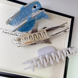 Gros plan de trois pinces à cheveux en acétate aux motifs de baleine et de requin