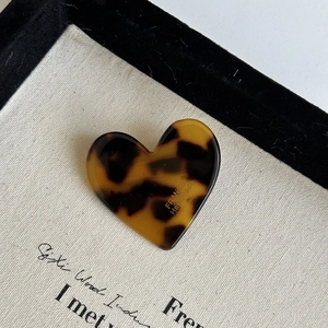 Macro detail of heart hair clip featuring classic leopard pattern and handmade engraving