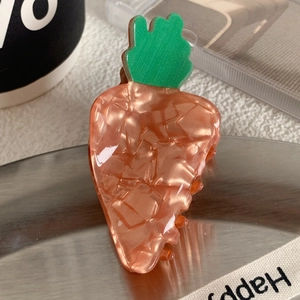 Détail d'une pince à cheveux en forme de carotte en acétate orange à texture marbrée