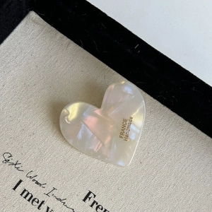 Detail view of heart-shaped cream resin hair clip with marble texture and France Handmade logo