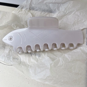 Détail d'une pince à cheveux en forme de poisson crème avec texture écailles et strass