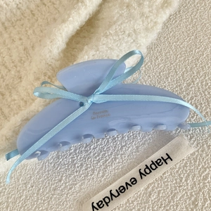Detail of light blue acetate hair claw clip with matching ribbon bow on cozy knit background