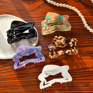 Five assorted star-shaped acetate hair claws with rhinestones on a wooden background